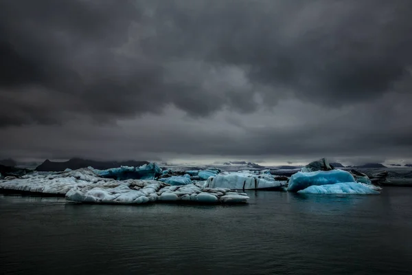 アイスランド南東部の氷河ラグーンであるジョクルサロンにはいくつかの氷河が浮かんでいる それらは多数であり ライトブルー 紺碧であり 白い反射があります 空は灰色 — ストック写真