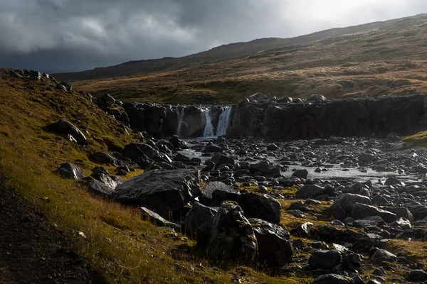 在冰岛有着可见瀑布的风景 水是清澈的蓝色 周围是布满青苔的黑色火山岩 — 图库照片