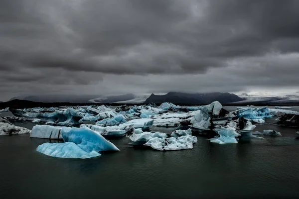 アイスランド南東部の氷河ラグーンであるジョクルサロンにはいくつかの氷河が浮かんでいる それらは多数であり ライトブルー 紺碧であり 白い反射があります 空は灰色 — ストック写真