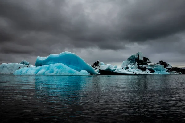 アイスランド南東部の氷河ラグーンであるジョクルサロンにはいくつかの氷河が浮かんでいる それらは多数であり ライトブルー 紺碧であり 白い反射があります 空は灰色 — ストック写真