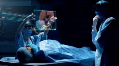 Artırılmış sanal gerçeklik holografik lens kulaklığı kullanan bir grup cerrah hasta organlarını gösteren sanal bir arayüzle etkileşim halindeler. Doktor karaciğeri analiz ediyor. Red Epic W Helyum 8k Sinema Kamerasında Çekim.