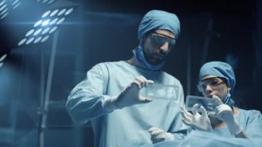 Profesyonel Cerrah ve Hasta Analiz Asistanı Ameliyat sırasında Şeffaf Telefonlar Verisi. Modern Hastane Ameliyathanesi. Kırmızı Epic-W Helyum Kamerada Çekim.