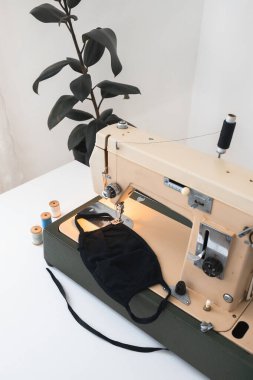 Dikiş makinesi olan ev işi, beyaz izole edilmiş arka planda koruyucu ilaç koronavirüs maskesi iplikleri.
