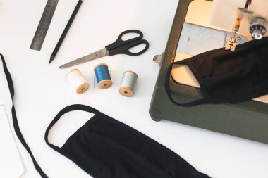Dikiş makinesi olan ev işi, beyaz izole edilmiş arka planda koruyucu ilaç koronavirüs maskesi iplikleri.