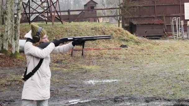 Mädchen schießt mit dem Jagdgewehr auf Ziele auf dem Schießstand. Kaliber 12
