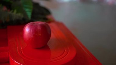 Kırmızı bir elma kırmızı bir yüzeyde uzanıyor.