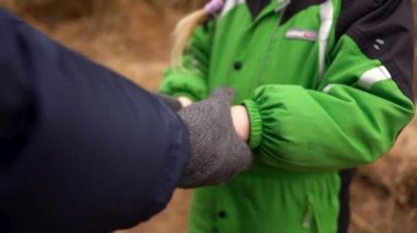 Kızın elleri üşümüş ve babası onu sıcak tutması için ona eldivenlerini vermiş.