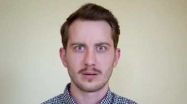 Sakallı, bıyıklı ve güzel saç stili olan yakışıklı genç bir adam, anlayış eksikliğine şaşırır ve korkar. Stüdyo portre kapağı beyazdır. Güzel dişleri ve mavi gözleri var..