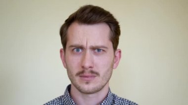 Sakallı, bıyıklı ve güzel saç stili olan yakışıklı genç bir adam, anlayış eksikliğine şaşırır ve korkar. Stüdyo portre kapağı beyazdır. Güzel dişleri ve mavi gözleri var..