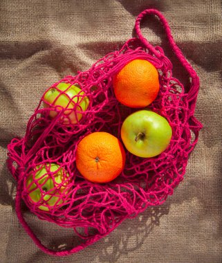 Portakallı kırmızı ip çanta ve meyveli yeşil elma.