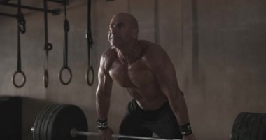 Spor salonunda ağırlık kaldıran bir adam.