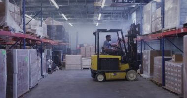 Nakliye deposunda forklift kullanan Afrikalı Amerikalı bir yönetici.