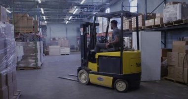 Nakliye deposunda forklift kullanan Afrikalı Amerikalı bir yönetici.