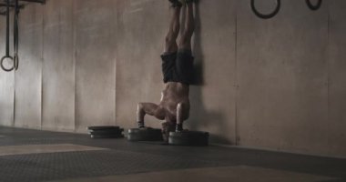 Spor salonunda amuda kalkan adam şınav çekiyor.