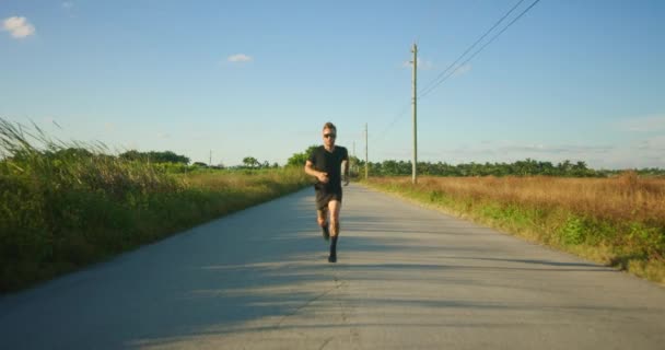 夕暮れ時の田舎道のトレーニングの男性ランナー — ストック動画