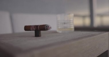 Adam gün batımında balkonda puro içiyor.