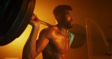 Adam karanlık spor salonunda çömeliyor.