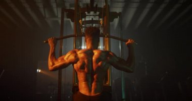 Adam karanlık spor salonunda sırt kaslarını çalıştırıyor.