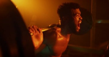 Spor salonunda çömelmiş bir adam.