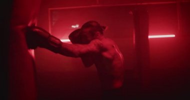 Erkek boksör boks antrenmanına kırmızı, siyah spor salonunda kum torbasıyla gider.