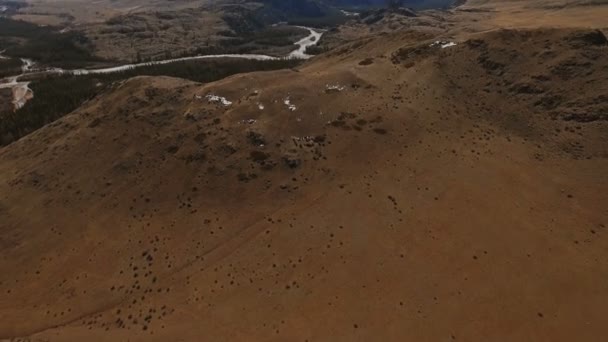 Ein Flug über ein wunderschönes Tal mit verschneiten Bergen in der Ferne — Stockvideo