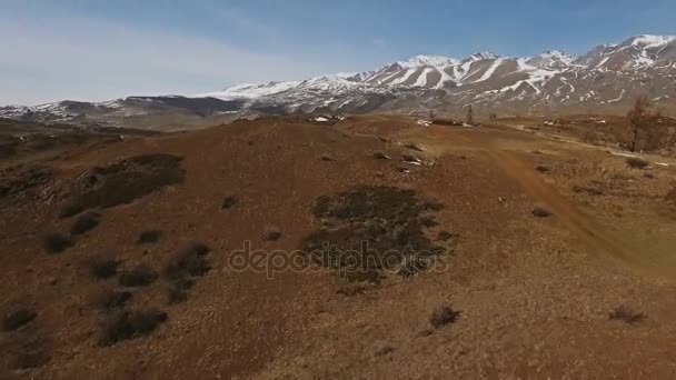 Un vuelo sobre un hermoso valle con montañas nevadas en la distancia — Vídeos de Stock