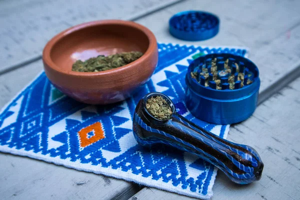 メキシコの繊維にマリファナの花 青い金属のグラインダー およびマリファナの粘土のボウルが詰め込まれたガラスパイプ メキシコでは大麻は合法です — ストック写真