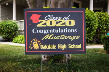 OAKDALE, CALIFORNIA / ABD - 29 Nisan 2020: Cemaatteki insanlar covid salgını sırasında 2020 mezunlarını tebrik etmek için ön bahçelerine tabelalar astılar.