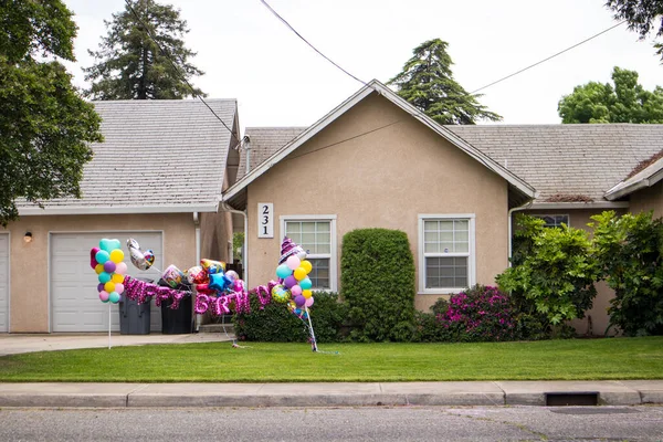 OAKDALE, CALIFORNIA / ABD - 29 Nisan 2020: Doğum günü balonları bir evin ön bahçesini arabayla geçerken doğum günü partisi için dekore ediyor