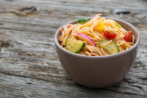 Açık hava pikniğinde tahta masada spagetti salatası.