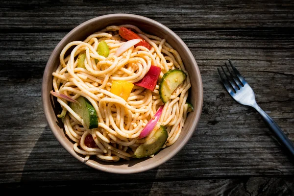 Açık hava pikniğinde tahta masada spagetti salatası.