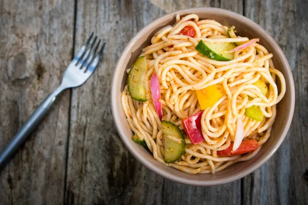 Açık hava pikniğinde tahta masada spagetti salatası.