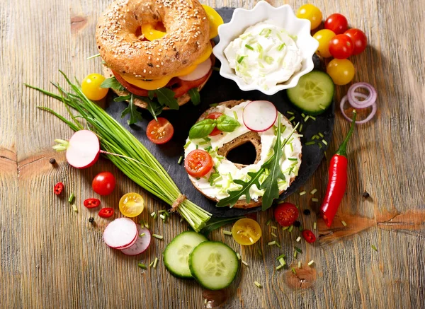 Vegetariánské bagel sendvič s čerstvou zeleninou, smetanový sýr, pažitku a rukolou, zdravý oběd — Stock fotografie