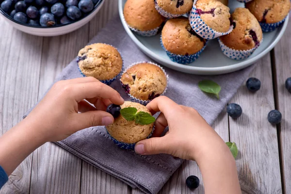 Ręce dziecka dekorowanie muffiny jagodowe, zdrowe domowe de — Zdjęcie stockowe