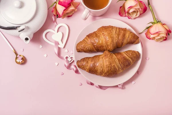 Café da manhã romântico com croissants, rosas e chá no backgr rosa — Fotografia de Stock