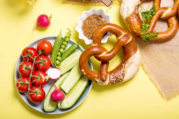 Pretzels και λαχανικά σε κίτρινο φόντο, γερμανικό παραδοσιακό — Φωτογραφία Αρχείου
