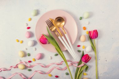 Paskalya sofrasında laleler, yumurtalar, çatal bıçak takımı, tabak, paskalya yemeği, paskalya arkaplanı.