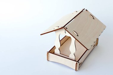 Renkli ahşap parçalardan yapılmış kuşların olmadığı bir dalda ormandaki kuşlar için besleyici. Sakin bir kış gününde manzara. Kuşlarla ve doğayla ilgilenmek, soğuk mevsimde yardım etmek..