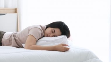 Asyalı kadın yorgun uyuyor ve akıllı telefonu elinden kayıp yere düşüyor. Sonra uyanıp dinlenmeye devam etmeden önce hasarı kontrol ediyor..