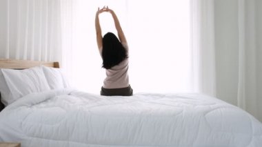 Asyalı genç kadın bütün gece derin uykudan uyanır. Sabahları ferahlamak için esneme hareketleri yapar..