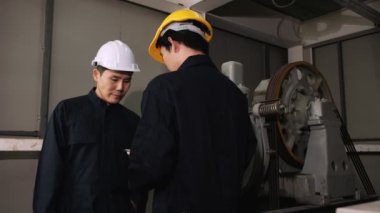 Yolcu asansörünü kontrol etmek için motor sisteminin sorunlarını çözmeye çalışan iki makine mühendisi..