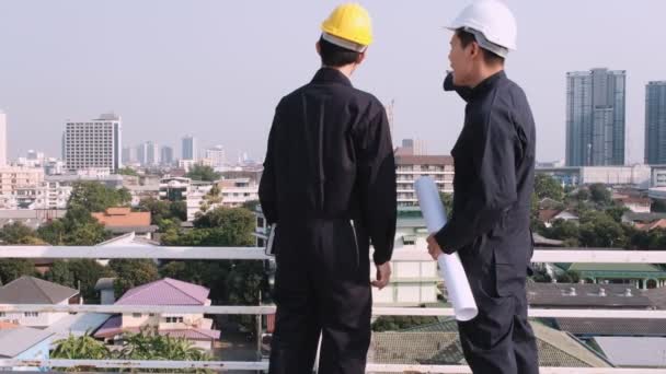 Dos Ingenieros Paran Techo Del Sitio Construcción Mirando Ciudad Con — Vídeos de Stock