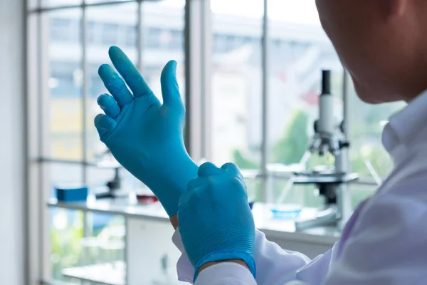 Laboratuvarda covid-19 hastalıkları için eldiven güvenliği takan bilim adamlarının yakın çekim elleri.