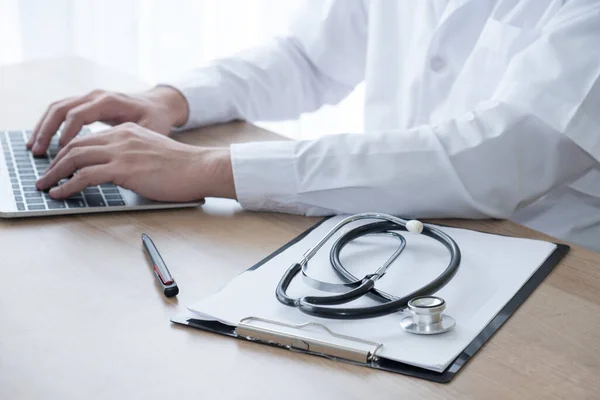 Uzman doktor, hastanın tıbbi kayıtlarını kontrol etmek için laptopunu ataç, sağlık ve tıbbi konsept ile steteskopla kullanıyor. Hastanedeki yaşlılar için danışmanlık ve teşhis.