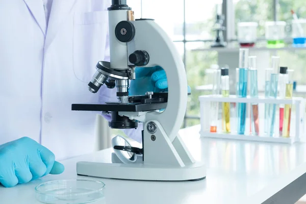 Laboratuvarda covid-19 veya corona virüsünü araştırmak için mikroskop kullanan bilim adamı. Tedavi ve aşı kavramını geliştirme.