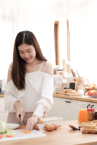 Kahvaltıda salata ve sandviç hazırlamak için jambon dilimleyen tatlı bir kadın..