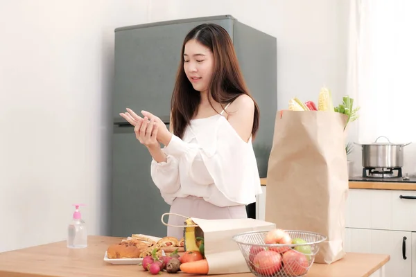 Tatlı Asyalı kadın mutfakta kahvaltıya hazırlanmadan önce Coronavirus 'u önlemek için jel alkolle ellerini yıkıyor..