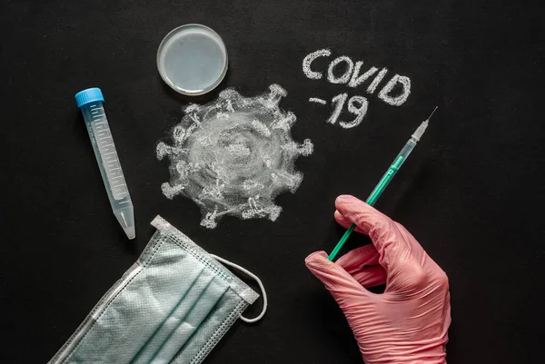 Syringe in hands in pink medical gloves at black chalkboard. Corona virus, mysterious viral pneumonia. Similar to MERS CoV or SARS virus. Health care and medical concept.