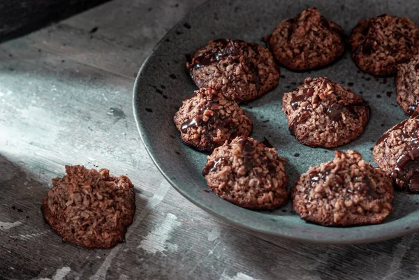 Homemade coconut cookies with cocoa, on a gray plate and shabby wooden background. Dark food photo.