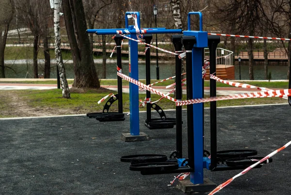 Açık hava spor ekipmanları bariyer bandıyla çekildi. Koronavirüs salgını sırasında karantina önlemleri.